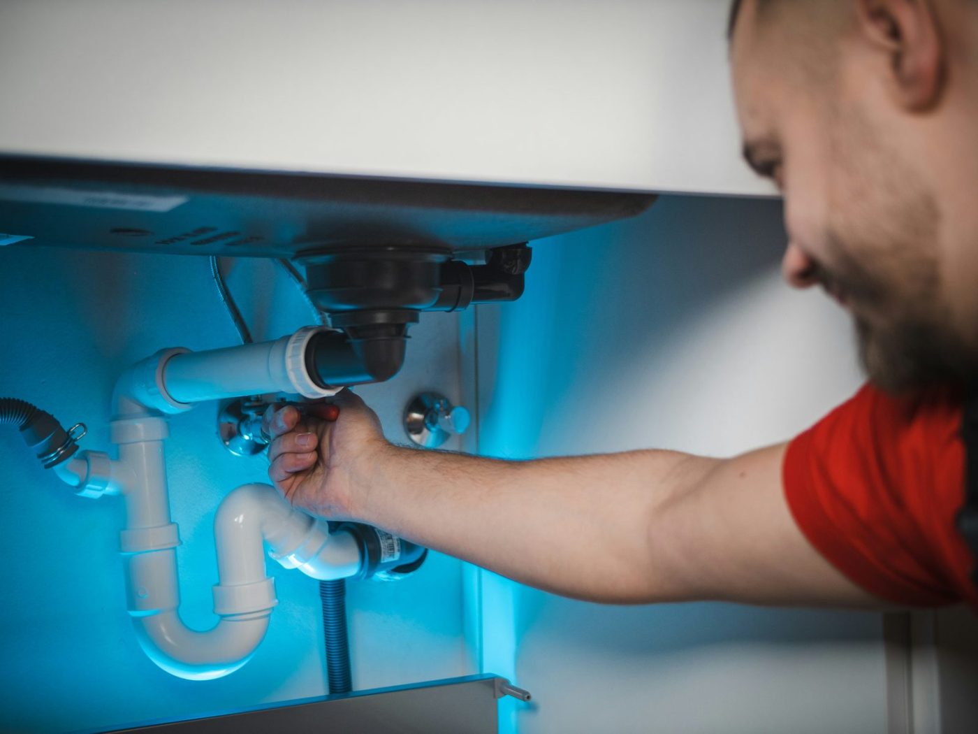 Plumber repairing pipework under a sink